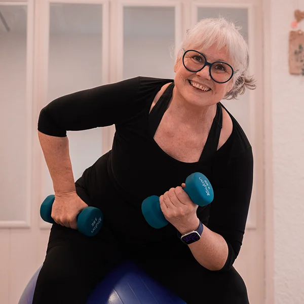 Die Inhaberin des Studios macht Übungen mit Gewichten