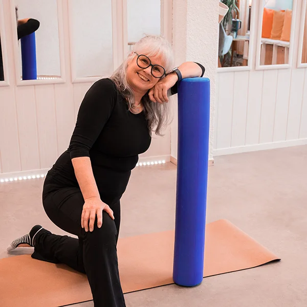 Die Inhaberin des Studios macht Übungen mit einer Pilates Rolle